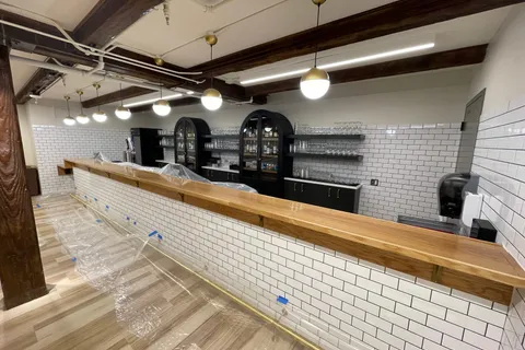 Restaurant bar with white subway tile, a butcher-block countertop, and exposed dark wood beams