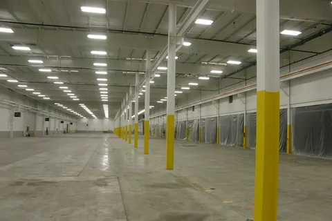 Painted white structural trusses and yellow support columns inside a large commercial warehouse