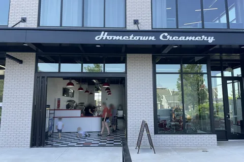 Hometown Creamery storefront with white brick, black-framed windows, and an open walk-up counter