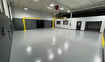 Shop bay with a glossy gray epoxy floor and yellow overhead cranes