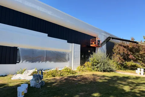 Commercial building exterior being painted from a boom lift