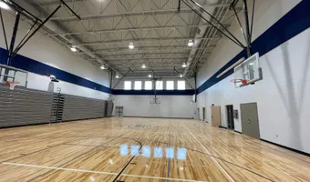 Finished gymnasium with a polished maple court, painted navy accent band, and steel roof trusses