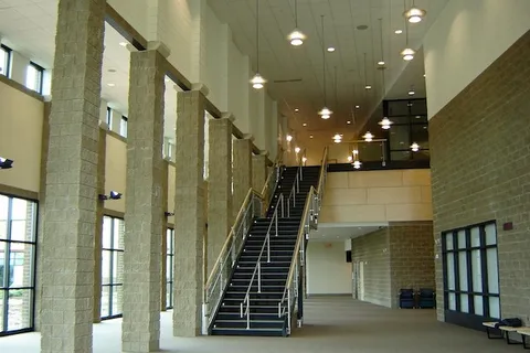 Two-story lobby with stone columns and an open staircase in an institutional building