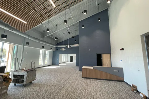 Two-story lobby with a wood-slat ceiling, navy accent wall, and carpet tile flooring