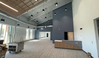 Two-story lobby with a wood-slat ceiling, navy accent wall, and carpet tile flooring