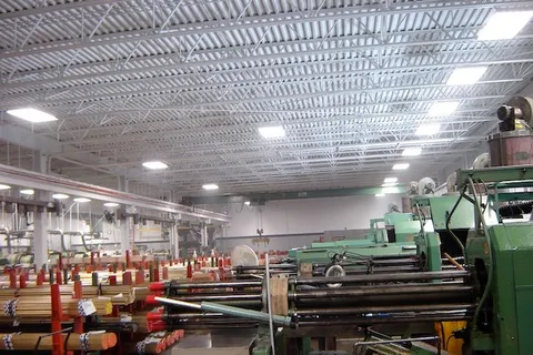 Painted overhead trusses and piping above a manufacturing production floor