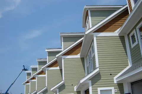 Row of townhomes with painted exterior siding and trim, boom lift in view